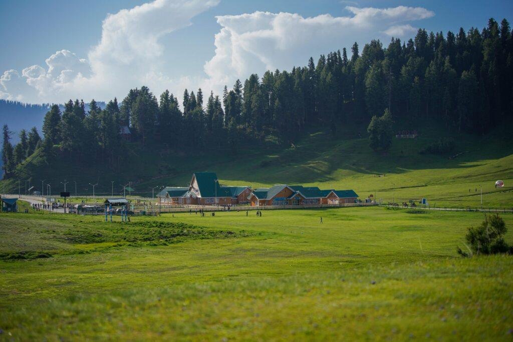 Panoramic hilltop view of Baisaran Valley’s lush green meadow and snow‑capped Pir Panjal mountains near Pahalgam, Kashmir, India
