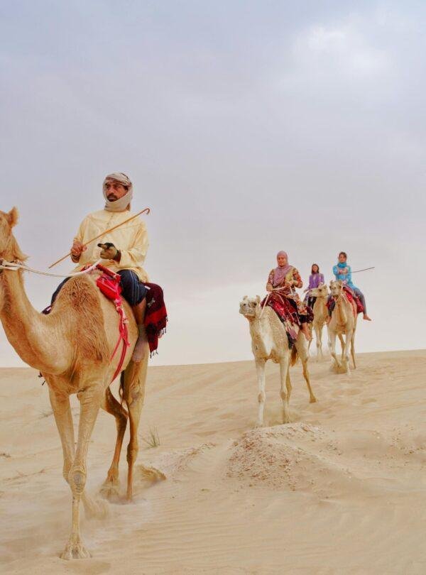 Camel ride in Dubai desert safari with golden sand dunes United Arab Emirates