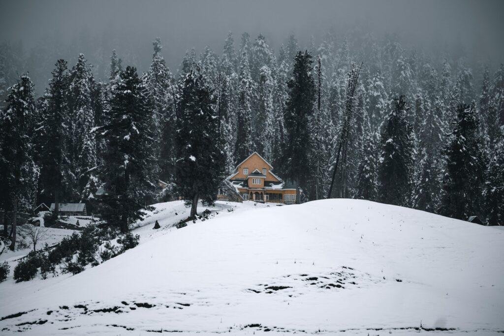 Couple in snowy meadows at Gulmarg winter landscape with snow‑covered Himalayan hills, Jammu & Kashmir, India