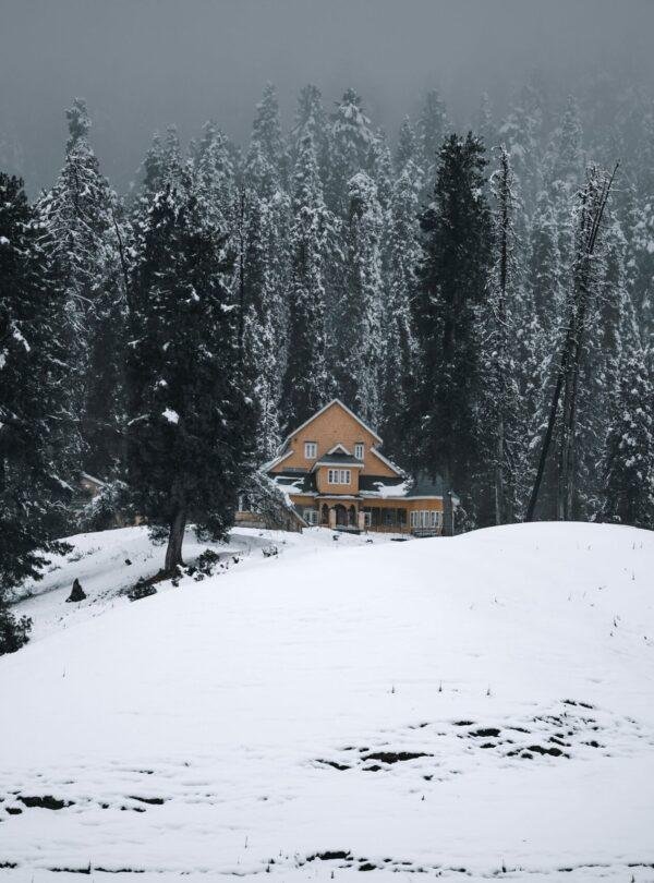 Couple in snowy meadows at Gulmarg winter landscape with snow‑covered Himalayan hills, Jammu & Kashmir, India