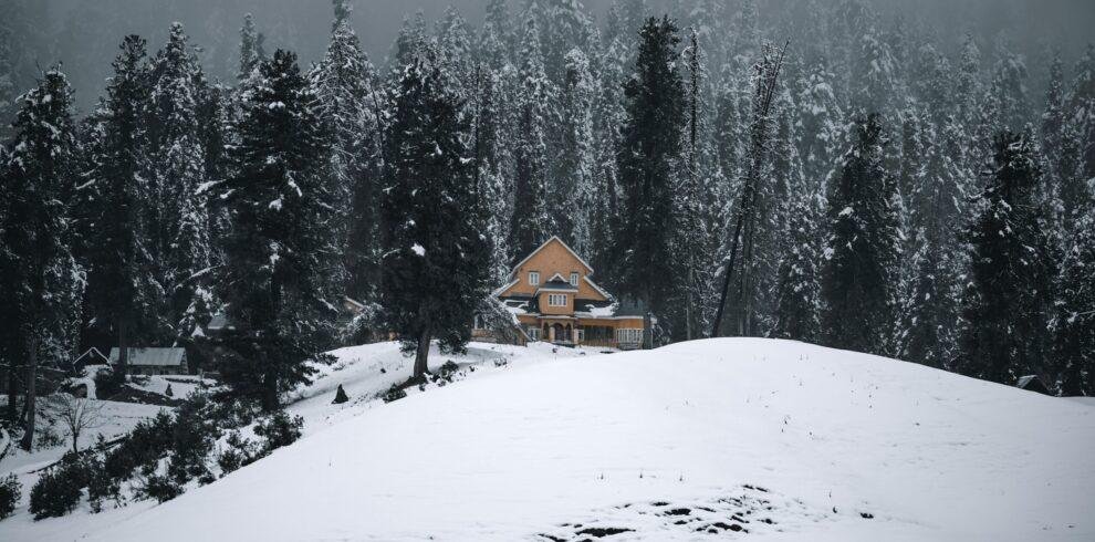 Couple in snowy meadows at Gulmarg winter landscape with snow‑covered Himalayan hills, Jammu & Kashmir, India